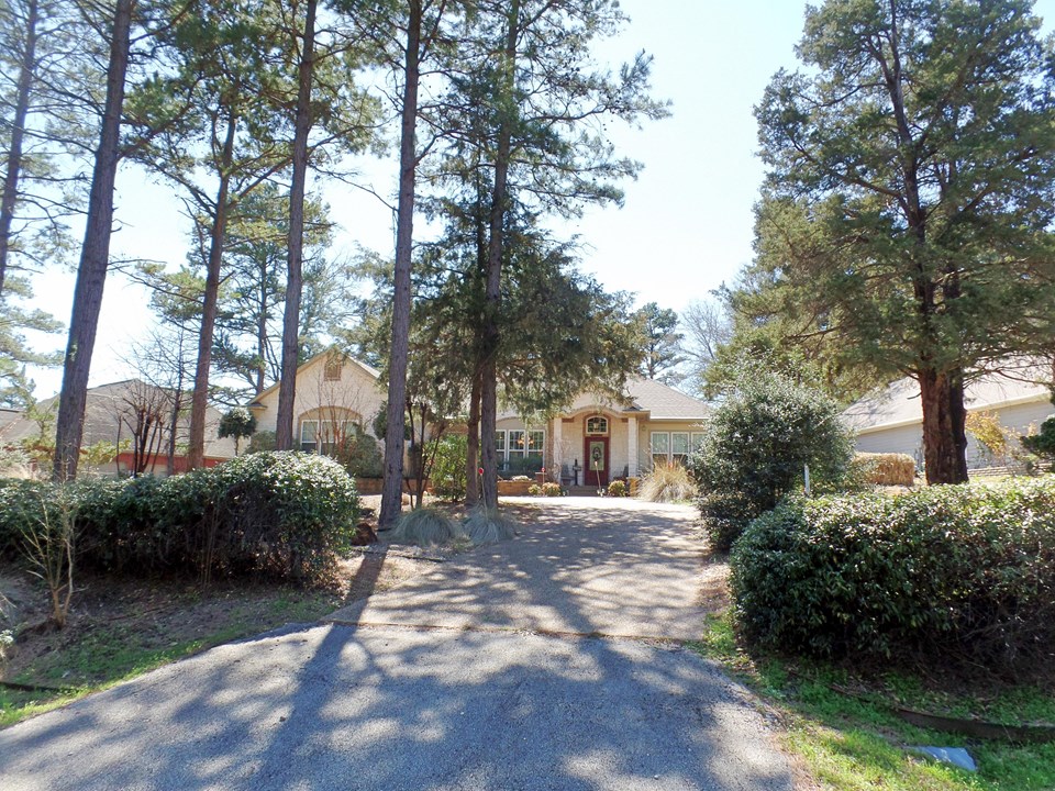 view from street of home on wooded lot with circular drive